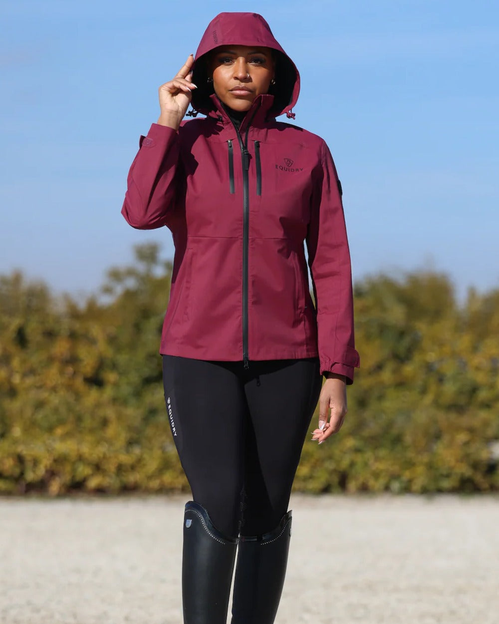Plum coloured Equidry Womens Varsha Jacket with Stowaway Hood on sand background 
