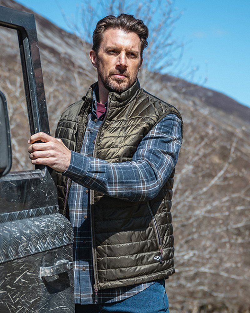 Man wearing a Hoggs of Fife quilted gilet outdoors beside an off-road vehicle