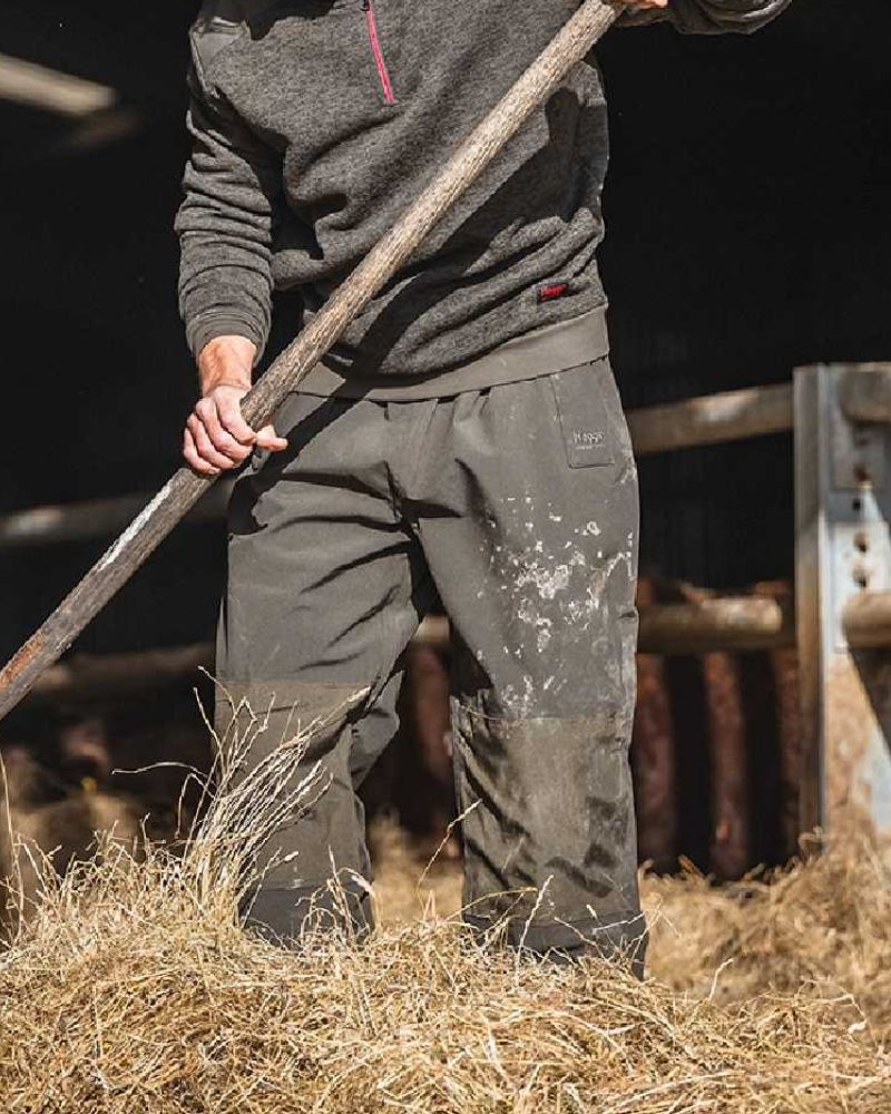 Person wearing Hoggs of Fife work trousers while working in a barn handling hay