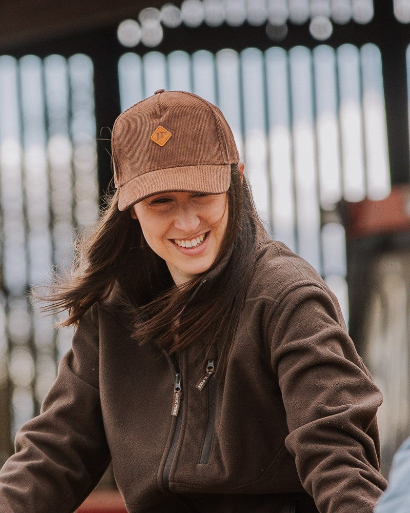 Woman wearing a Jack Pyke baseball cap and fleece jacket in a farm setting
