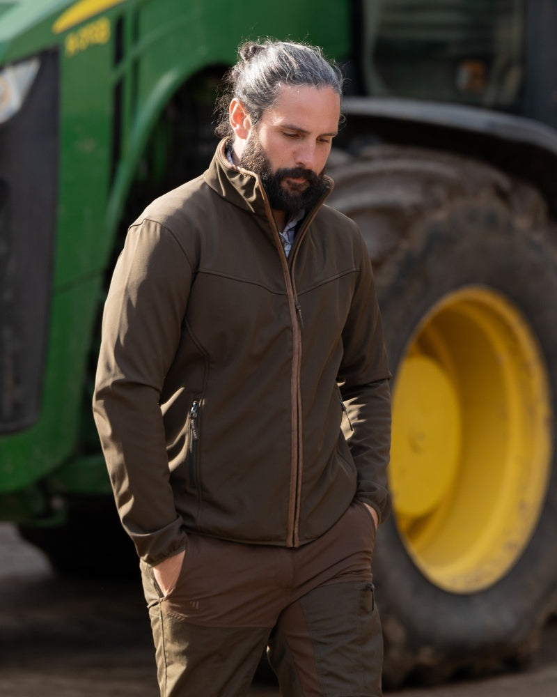 Man wearing a Jack Pyke outdoor jacket beside a tractor on a farm
