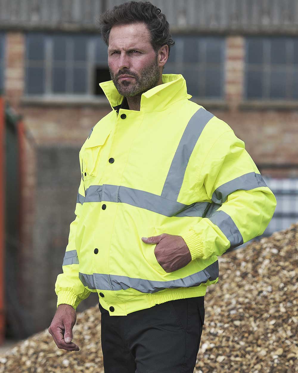 Workman wearing Yellow Fort Hi Vis Waterproof Bomber Jacket with reflective strips in Yellow 