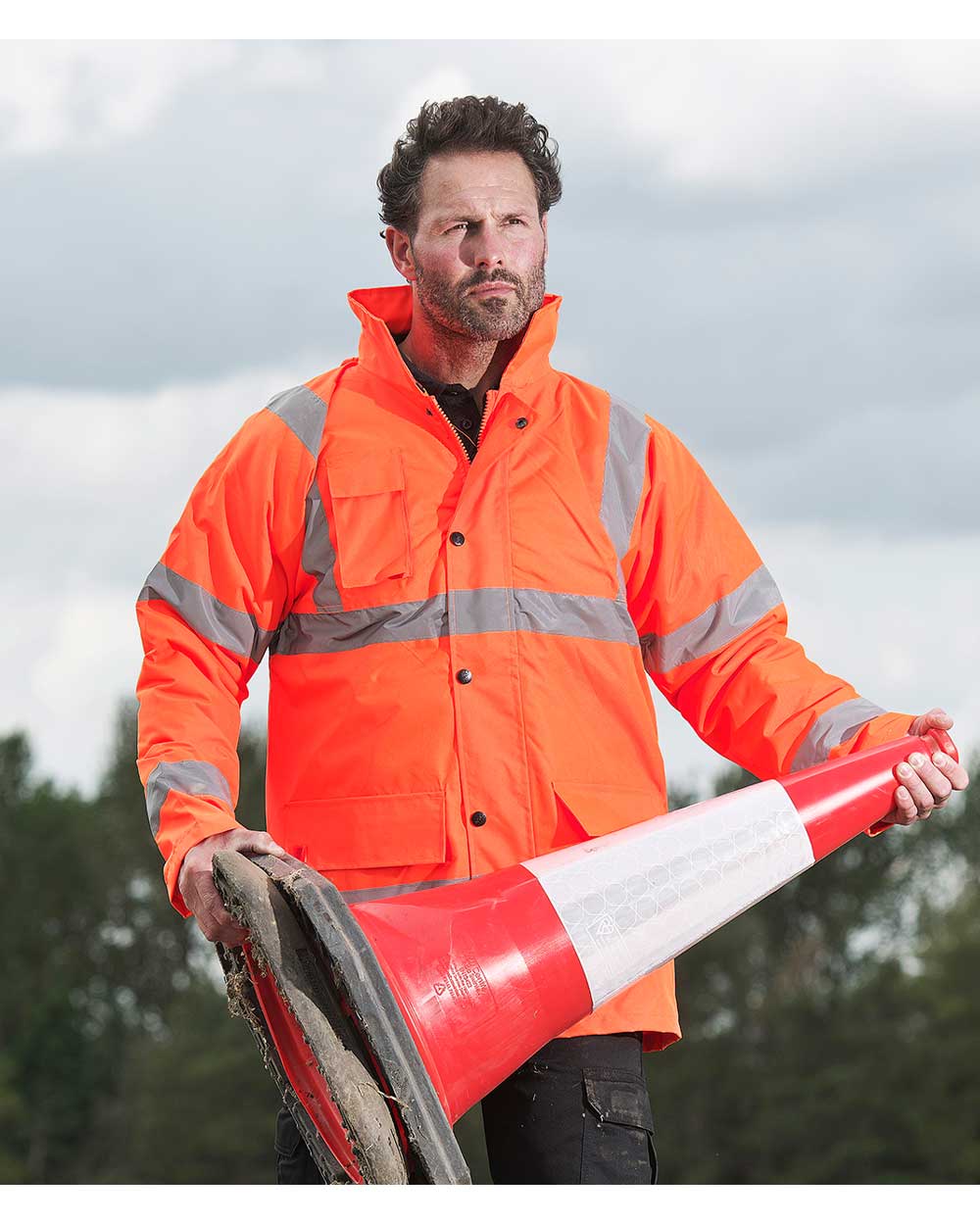 Man with road cone wearing Fort Workwear Quilted Jacket in orange 