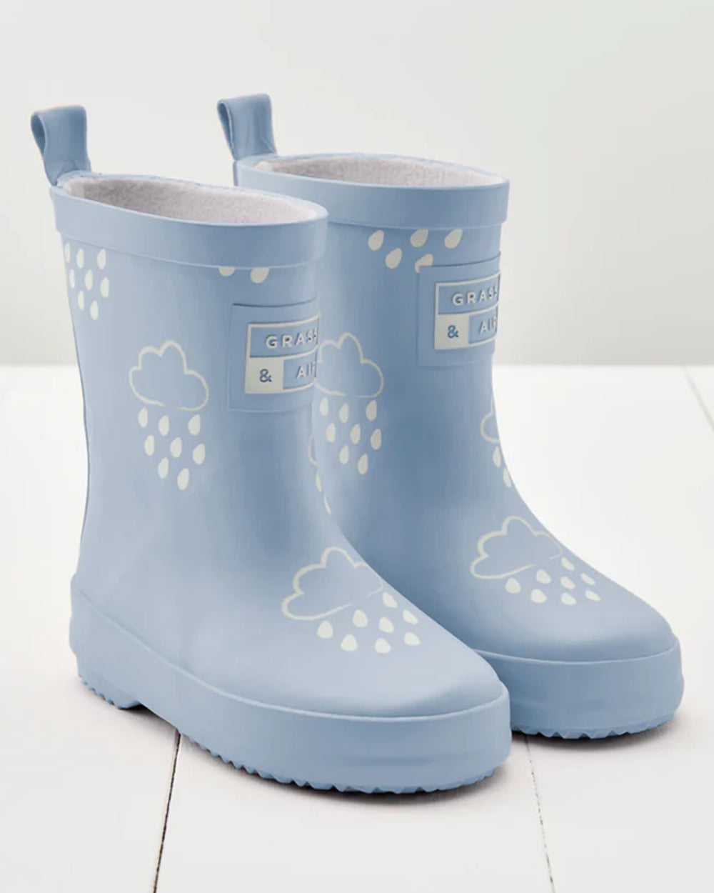Baby Blue coloured Grass &amp; Air Childrens Colour-Revealing Wellies on wooden table background 