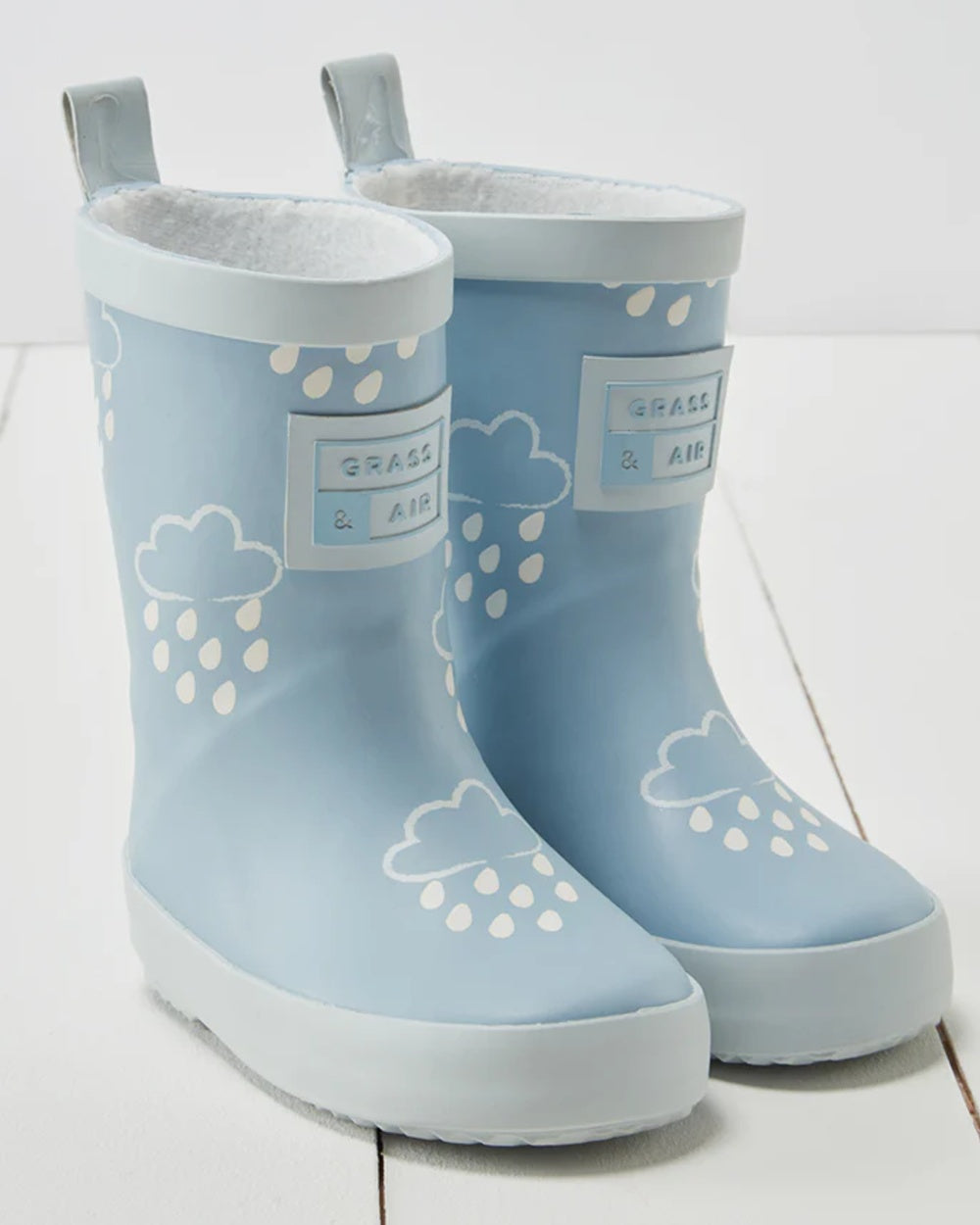 Ice Blue coloured Grass &amp; Air Childrens Colour-Revealing Wellies on wooden table background 