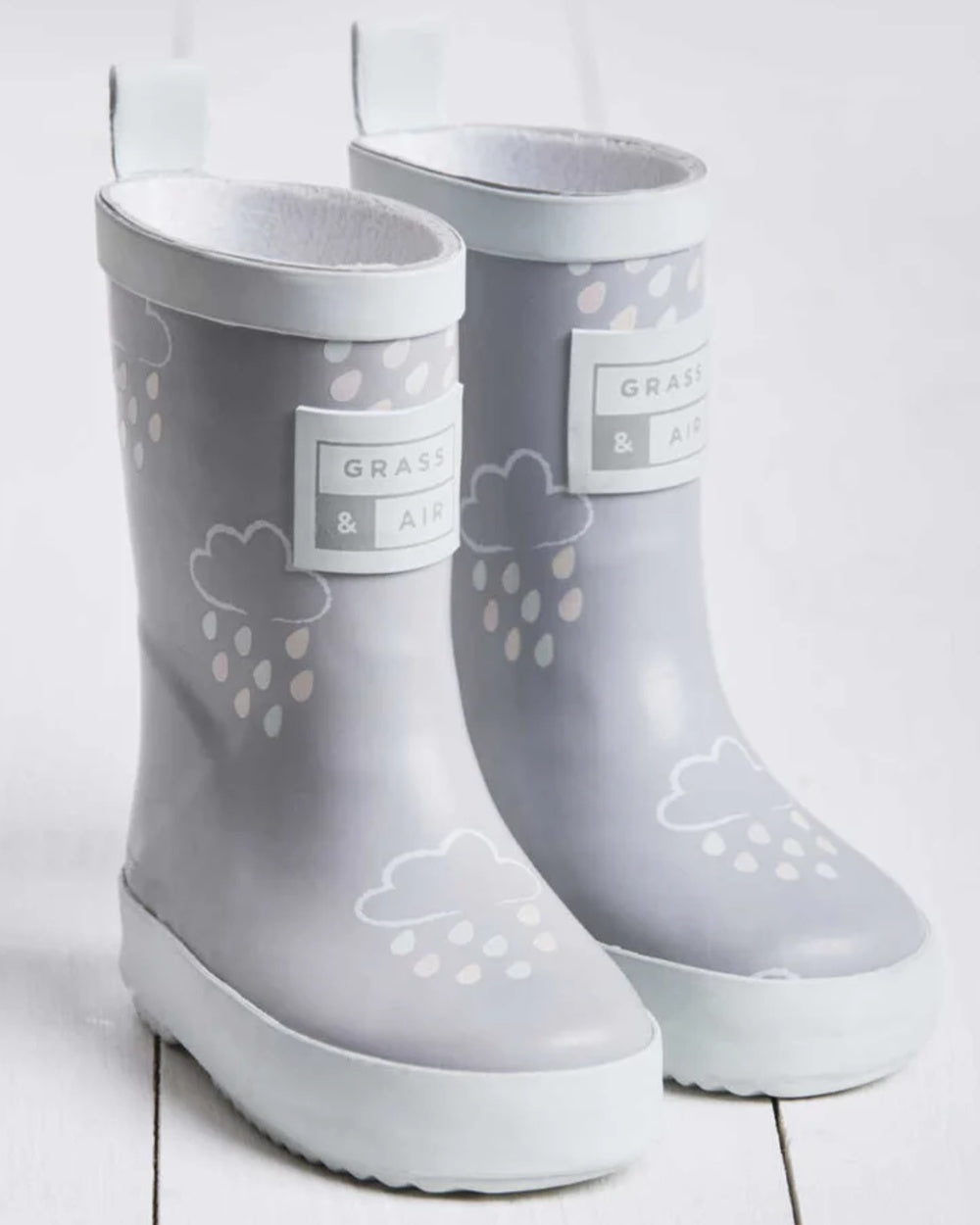 Light Grey coloured Grass &amp; Air Childrens Colour-Revealing Wellies on wooden table background 