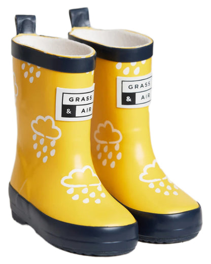 Yellow coloured Grass &amp; Air Childrens Colour-Revealing Wellies on white table background 