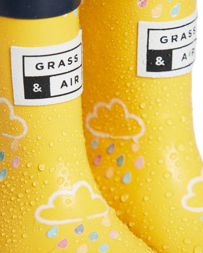 Yellow coloured Grass &amp; Air Childrens Colour-Revealing Wellies on white table background 
