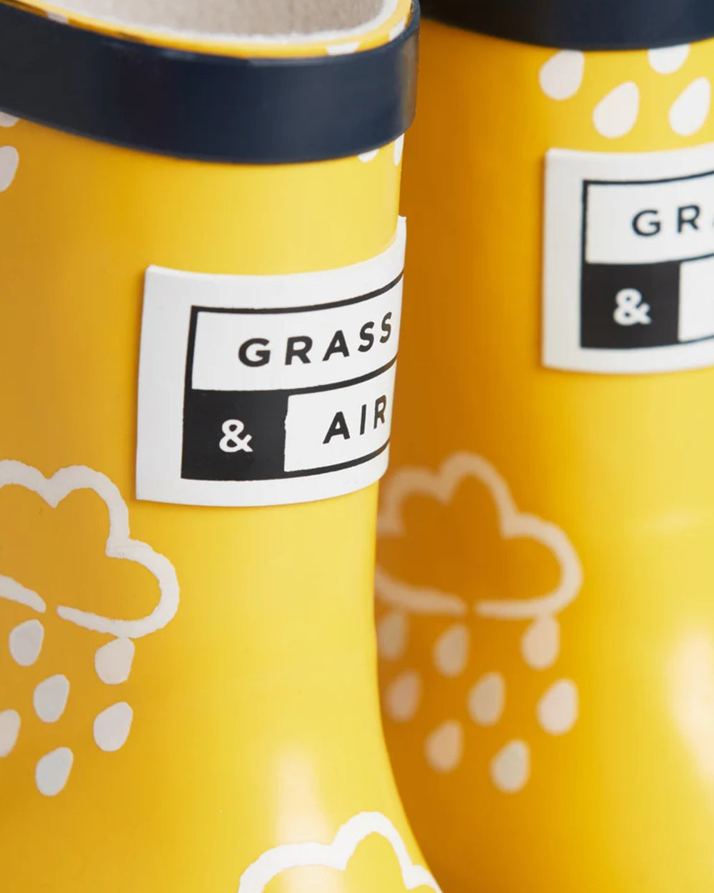 Yellow coloured Grass &amp; Air Childrens Colour-Revealing Wellies on white table background 