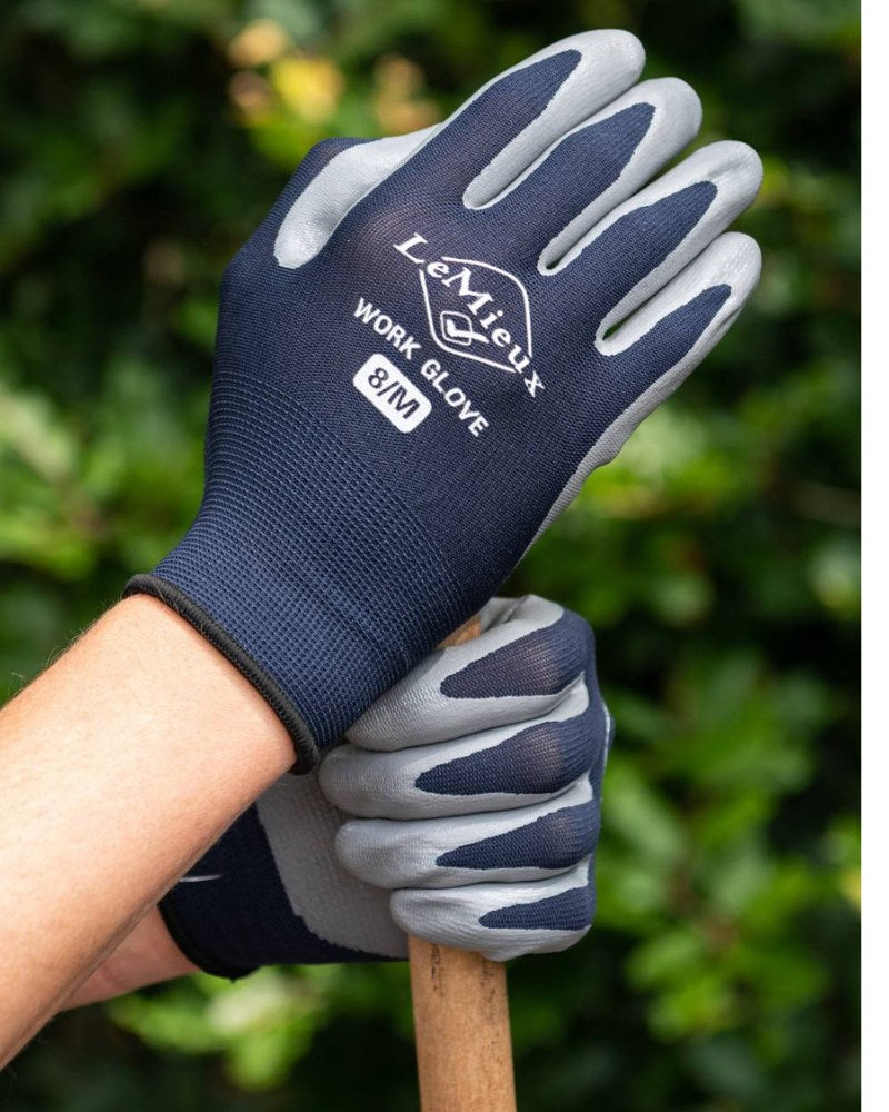 Person wearing LeMieux work gloves while holding a garden tool outdoors