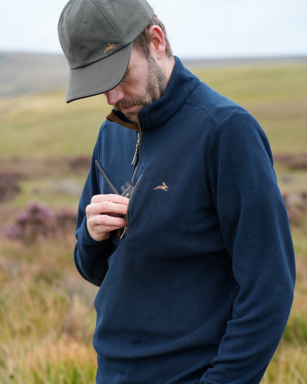 Model wearing a navy coloured Harehill Varden Quarter Zip Fleece on a moorland background 