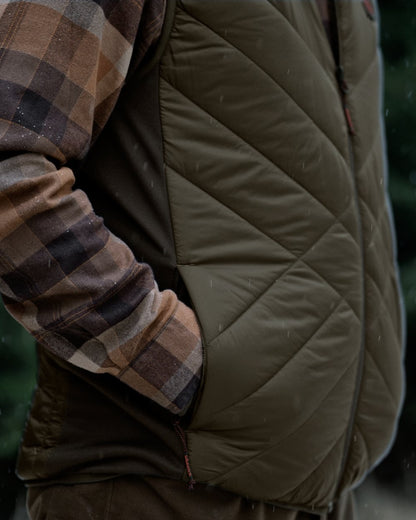 Willow Green Shadow Brown Coloured Harkila Heat Insulated Waistcoat on Forest Background 