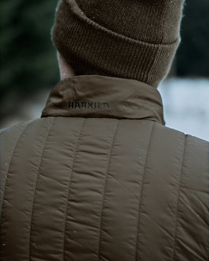 Willow Green Shadow Brown Coloured Harkila Heat Insulated Waistcoat on Forest Background 