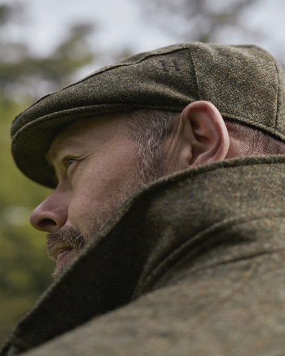 Forest Green Herringbone Coloured Harkila Kenmore Classic Flat Cap on outdoor background 