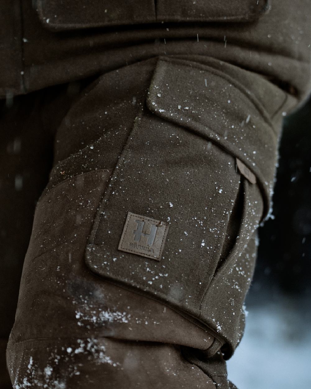Dark Hunting Green Shadow Brown coloured Harkila Kodiak CleverWool HSP Insulated Trousers on winter background 