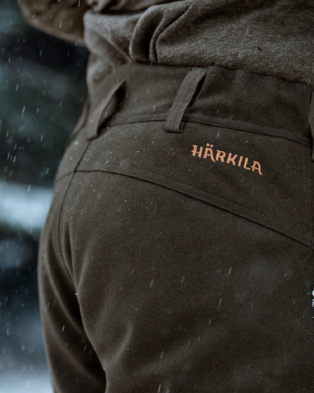 Dark Hunting Green Shadow Brown coloured Harkila Kodiak CleverWool HSP Insulated Trousers on winter background 