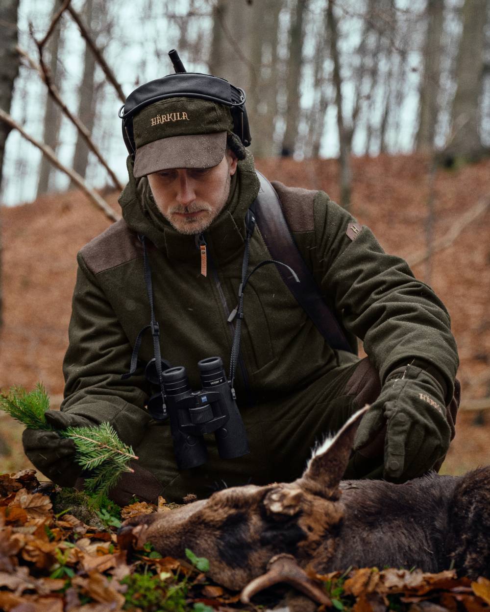 Willow Green coloured Harkila Metso Hybrid Jacket on blurry forest background 