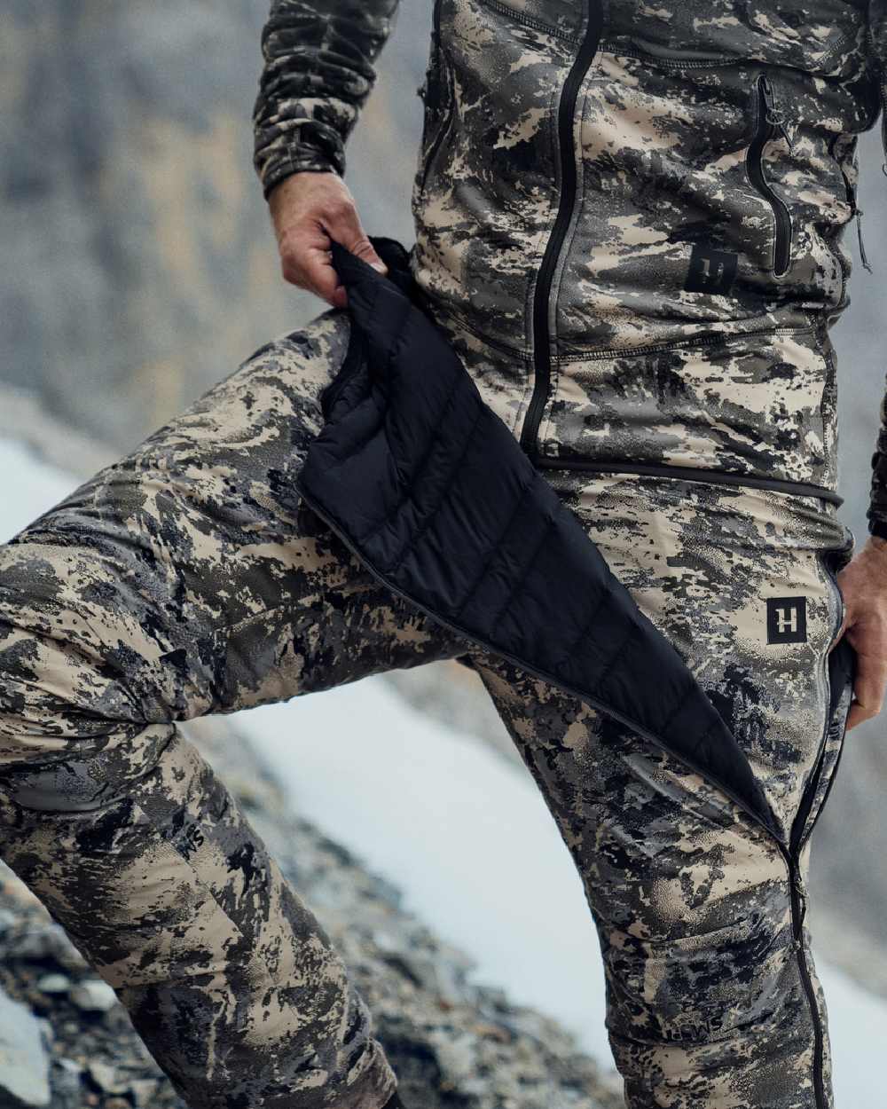 AXIS Mountain Coloured Harkila Mountain Hunter Expedition Packable Down Trousers on snow background 