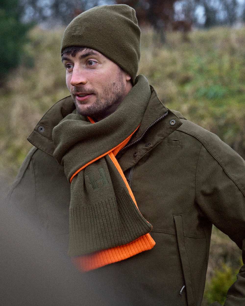 Willow Green Orange Coloured Harkila Reversible Scarf on outdoor background 