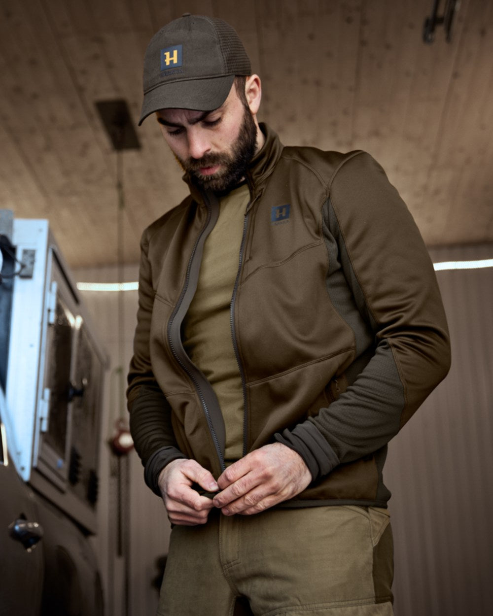 Willow Green Deep Brown Coloured Harkila Scandinavian Fleece Jacket on house background 
