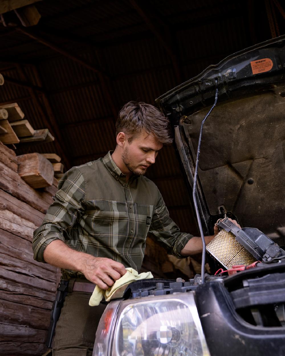 Willow Green coloured Harkila Anker Long Sleeve Shirt worn by man working on an engine in a farm