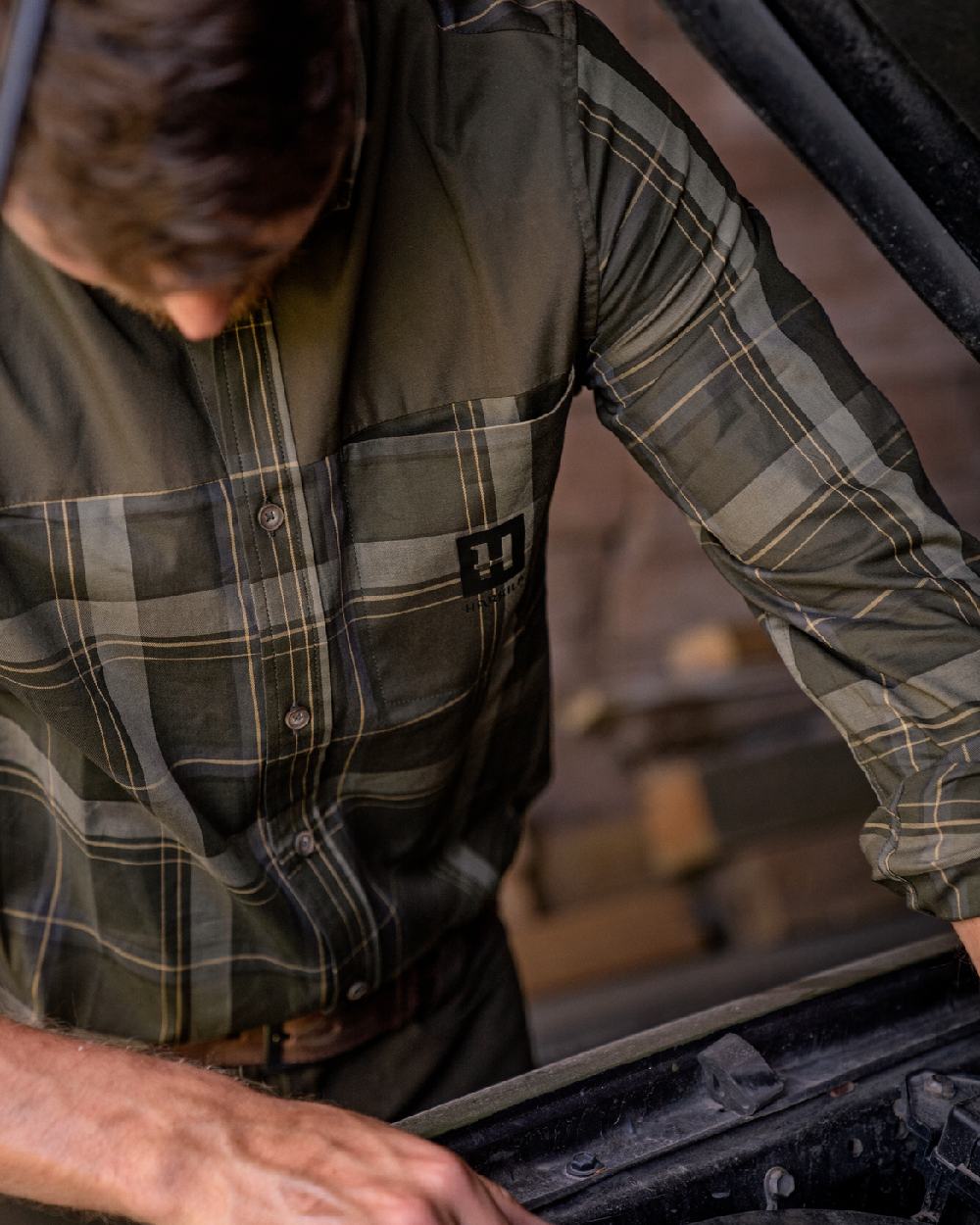 Willow Green coloured Harkila Anker Long Sleeve Shirt worn by man working on an engine in a farm