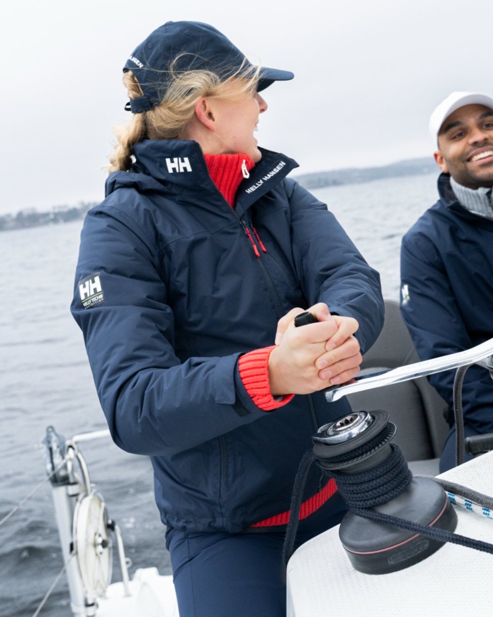 Navy coloured Helly Hansen Mens Crew Hooded Midlayer Jacket on sea background 
