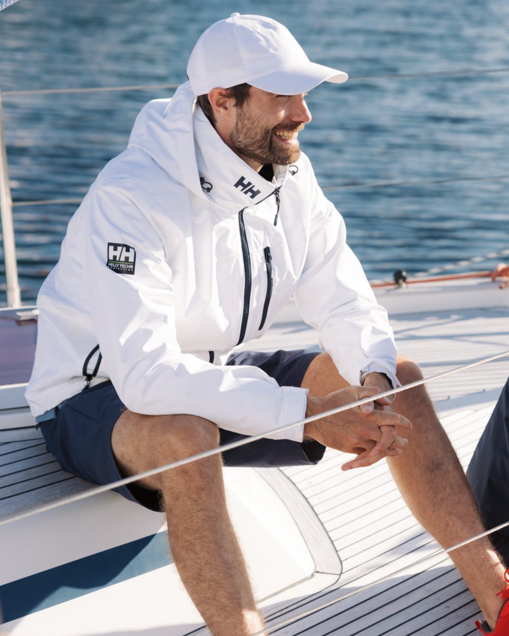 White coloured Helly Hansen Mens Crew Hooded Midlayer Jacket on sea background 