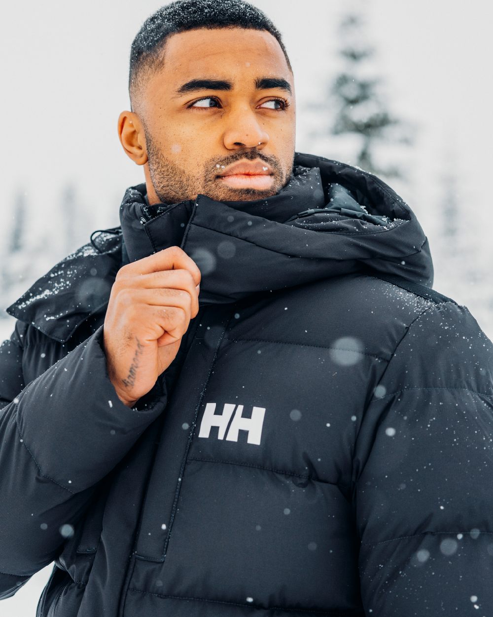 Black Coloured Helly Hansen Mens Explorer Puffy Jacket on snow background 