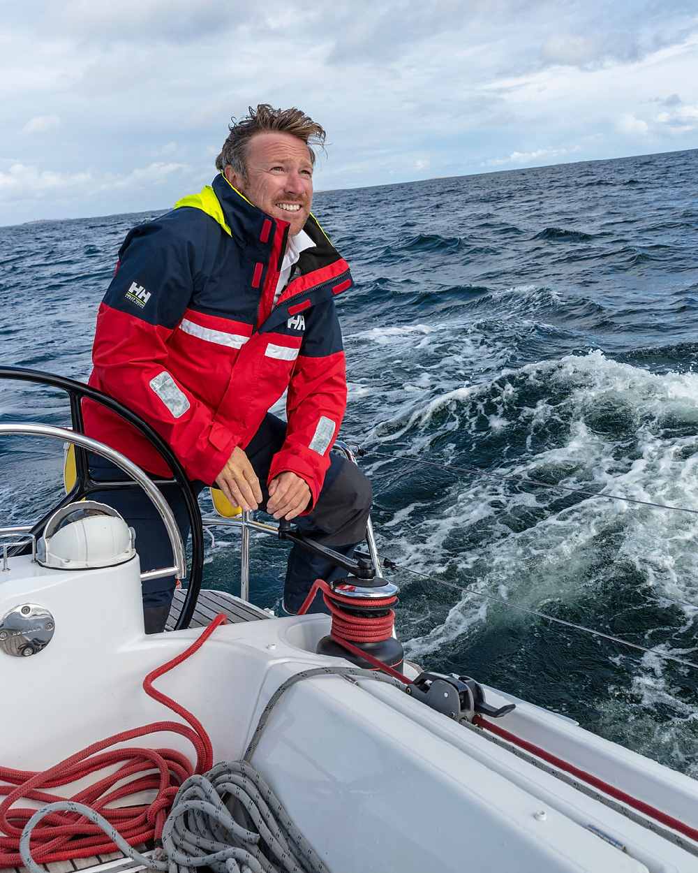 Red coloured Helly Hansen Mens Pier 4.0 Jacket on sea background 