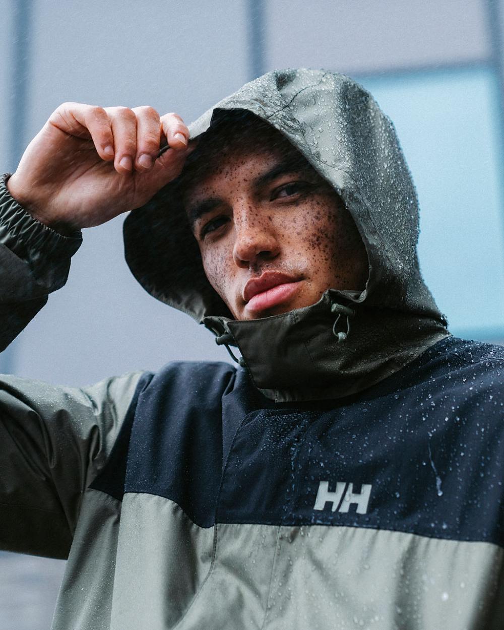 Lav Green coloured Helly Hansen Mens Vancouver Rain Jacket on blurry background 