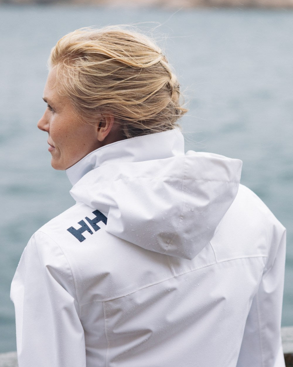 White Coloured Helly Hansen Womens Crew Hooded Midlayer Sailing Jacket 2.0 On A sea Background 