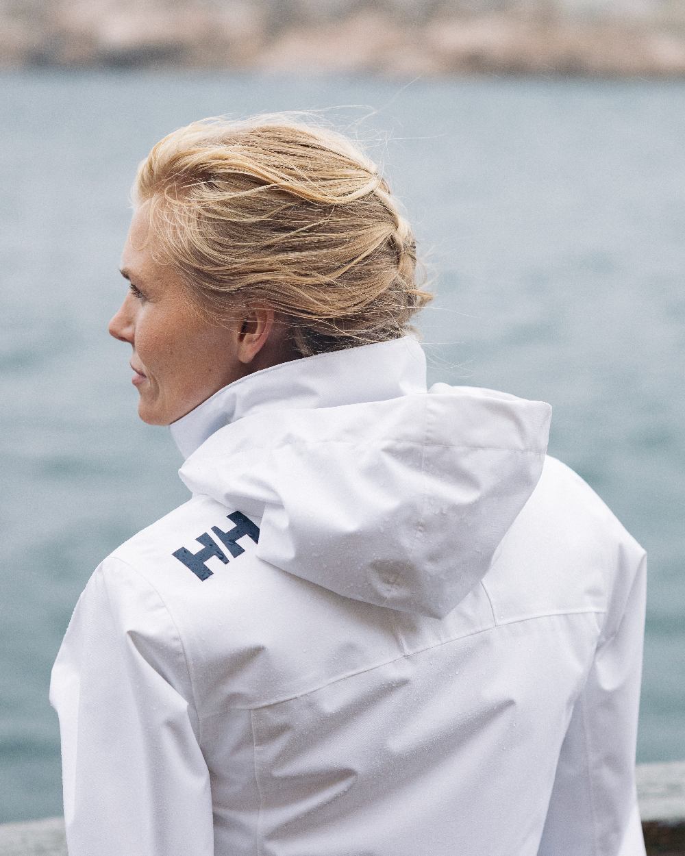 White Coloured Helly Hansen womens crew hooded sailing jacket 2.0 on outdoor background 