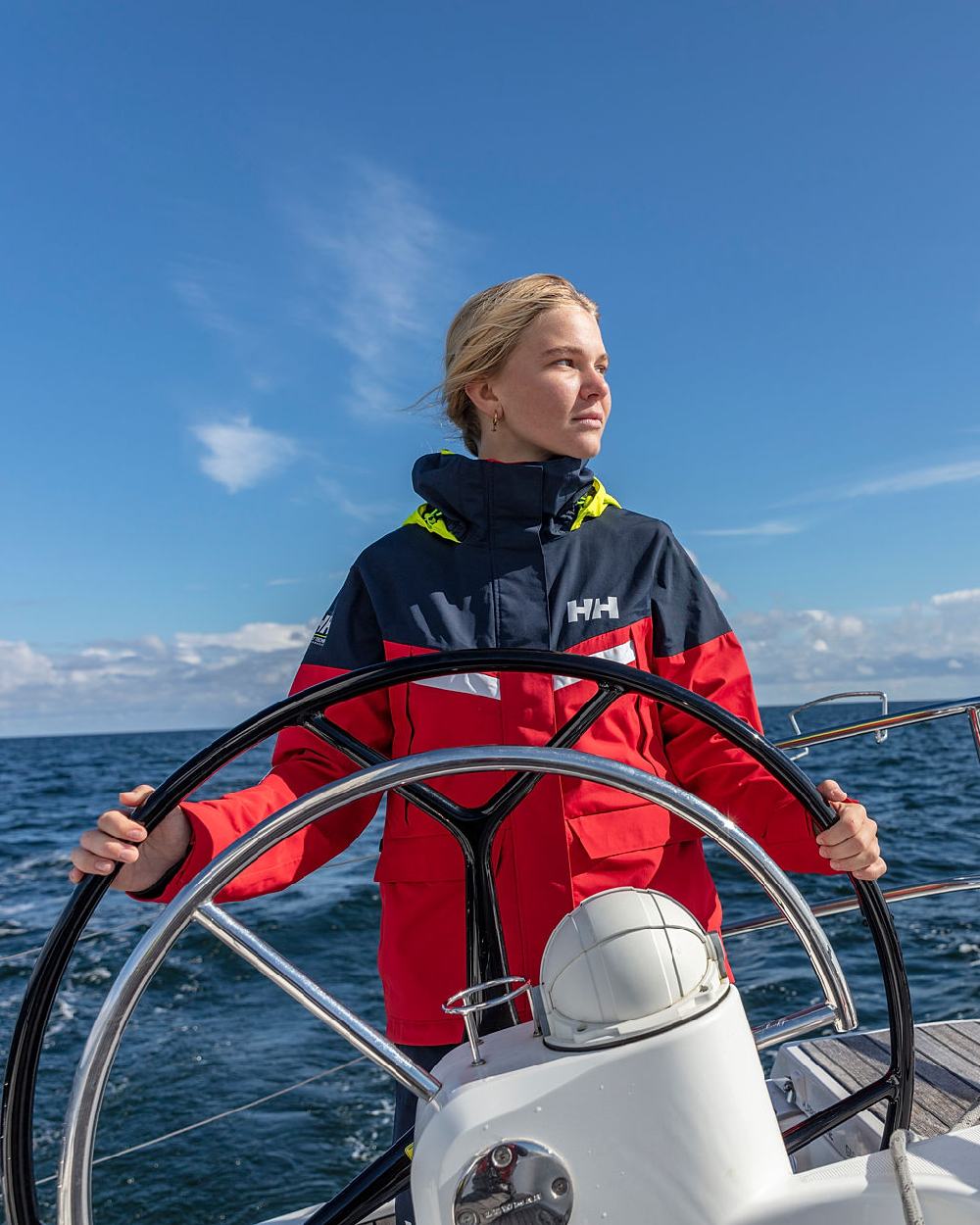 Red coloured Helly Hansen Womens Pier 4.0 Jacket on sea background 