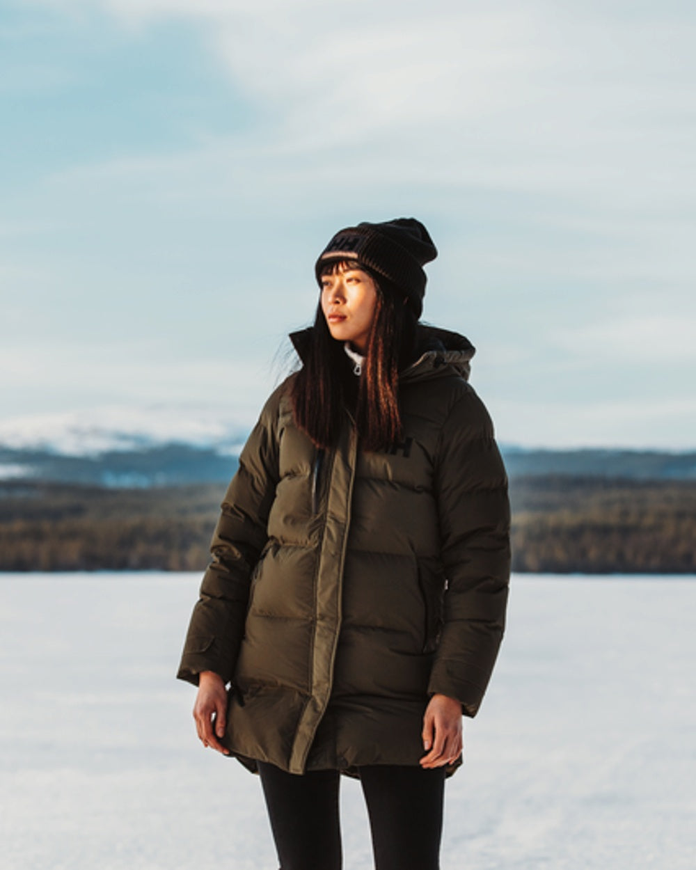 Utility Green Helly Hansen Adore Ladies Puffy Parka on snow background 