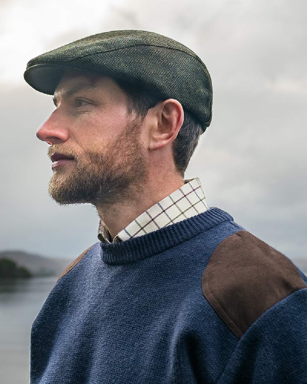 Green Coloured Hoggs of Fife Herringbone Waterproof Tweed Flat Cap on sky background 