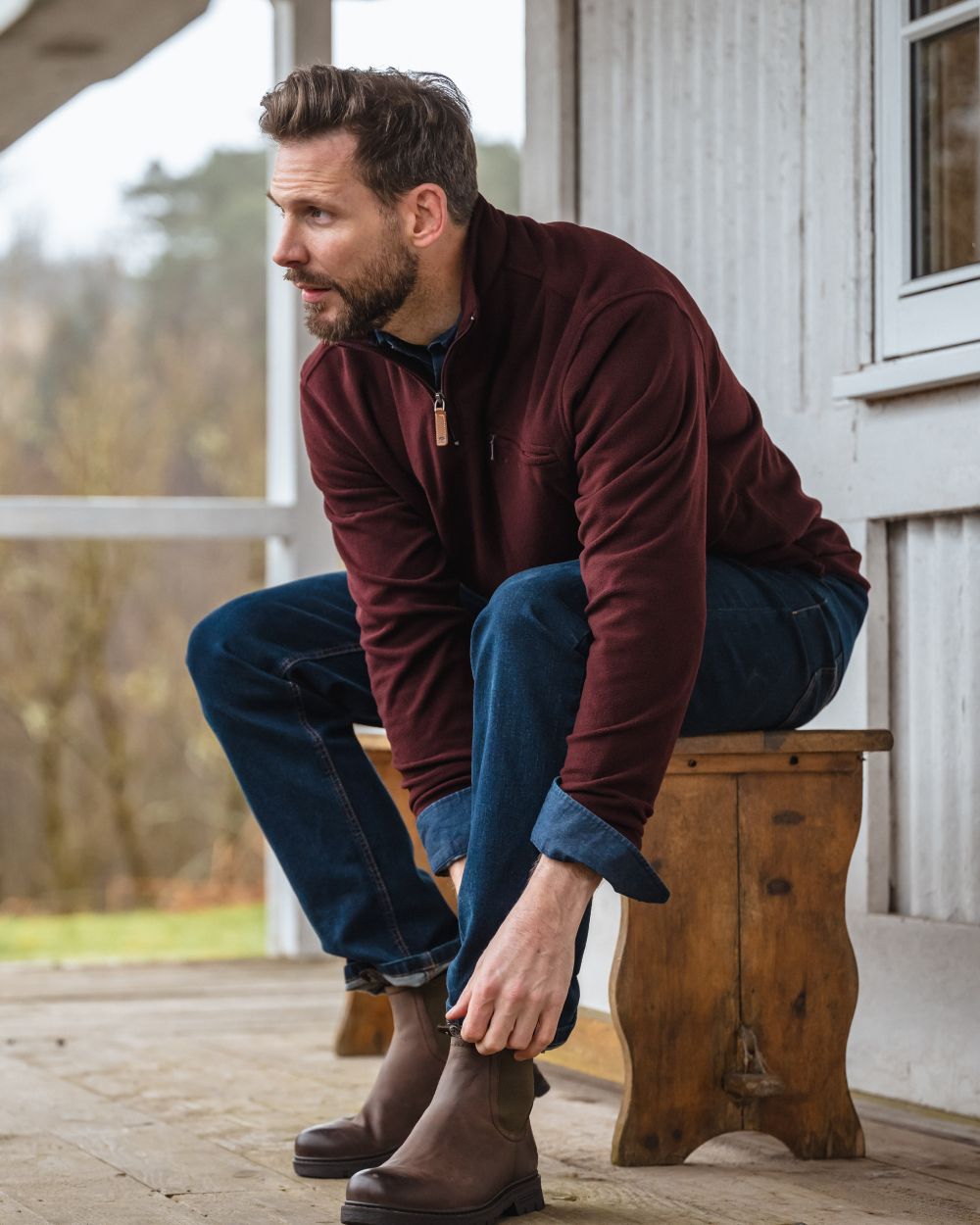 Burgundy coloured Hoggs of Fife Islander 1/4 Zip Micro Fleece Shirt with model sitting on bench 