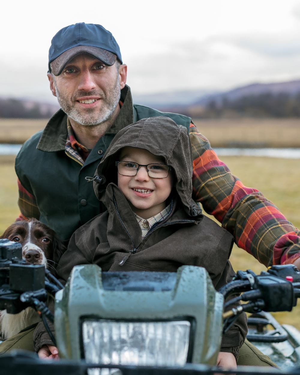 Dark Green Coloured Hoggs of Fife Junior Struther Waterproof Smock on countryside background 