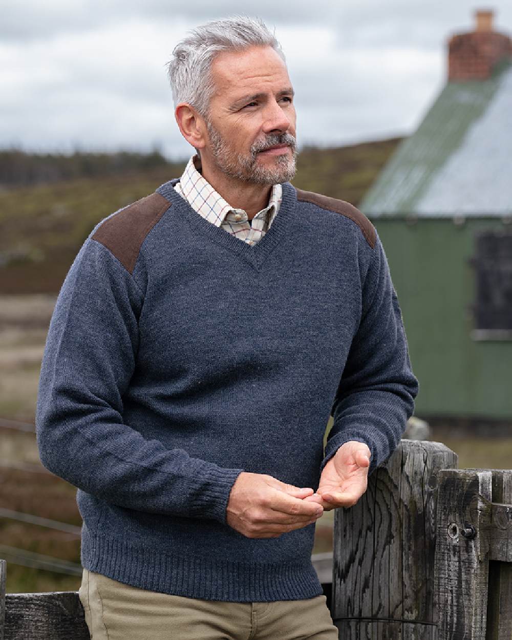 Storm Blue coloured Hoggs of Fife Melrose II V Neck Pullover on countryside background 