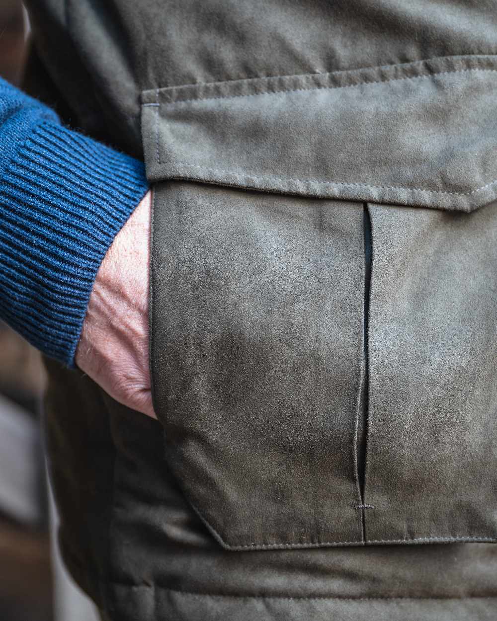 Loden coloured Hoggs of Fife Mens Glenbervie Quilted Gilet on blurry background 