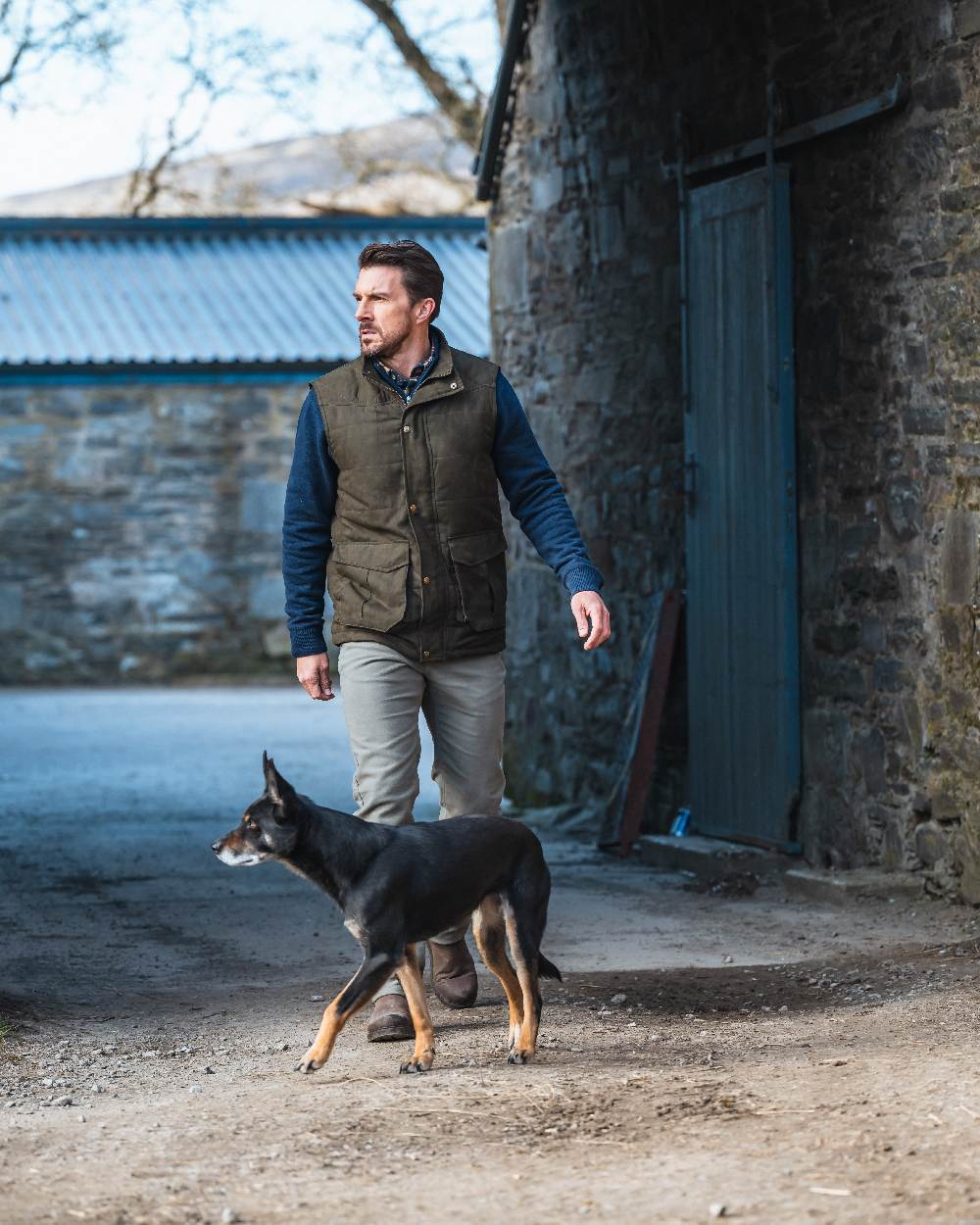 Loden coloured Hoggs of Fife Mens Glenbervie Quilted Gilet on house background 