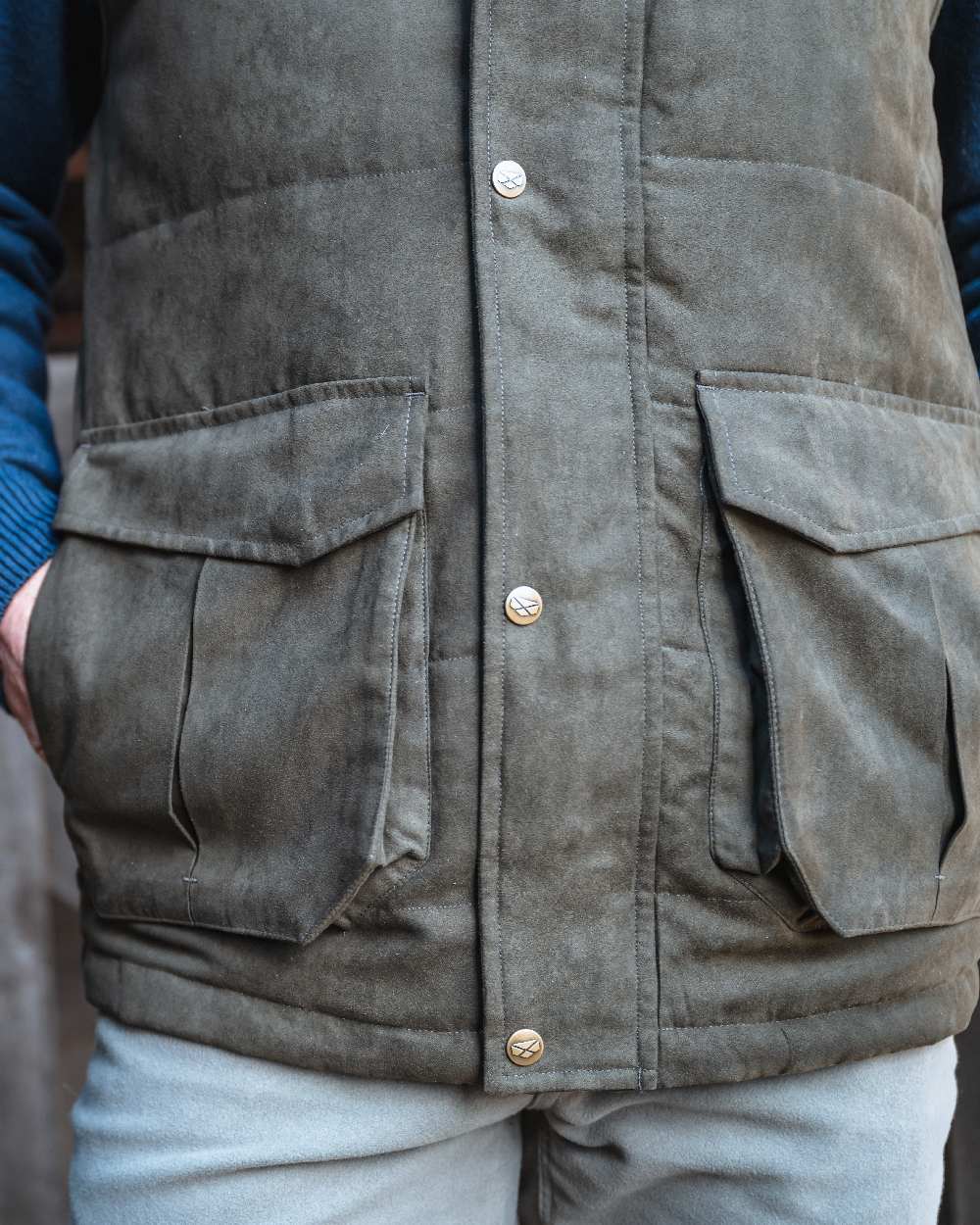 Loden coloured Hoggs of Fife Mens Glenbervie Quilted Gilet on blurry background 