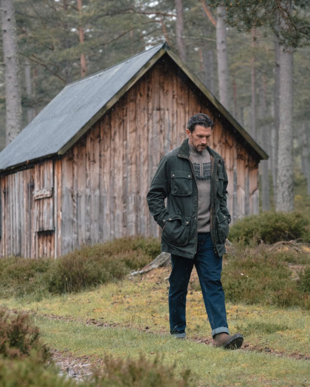 Dark Green coloured Hoggs of Fife Mens Linton Waxed Jacket on forest background 