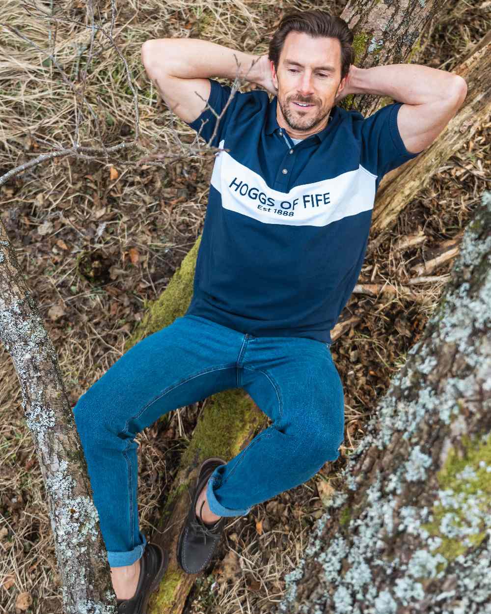 Navy Coloured Hoggs of Fife Mens Stewart Block Pique Polo Shirt on forest background 