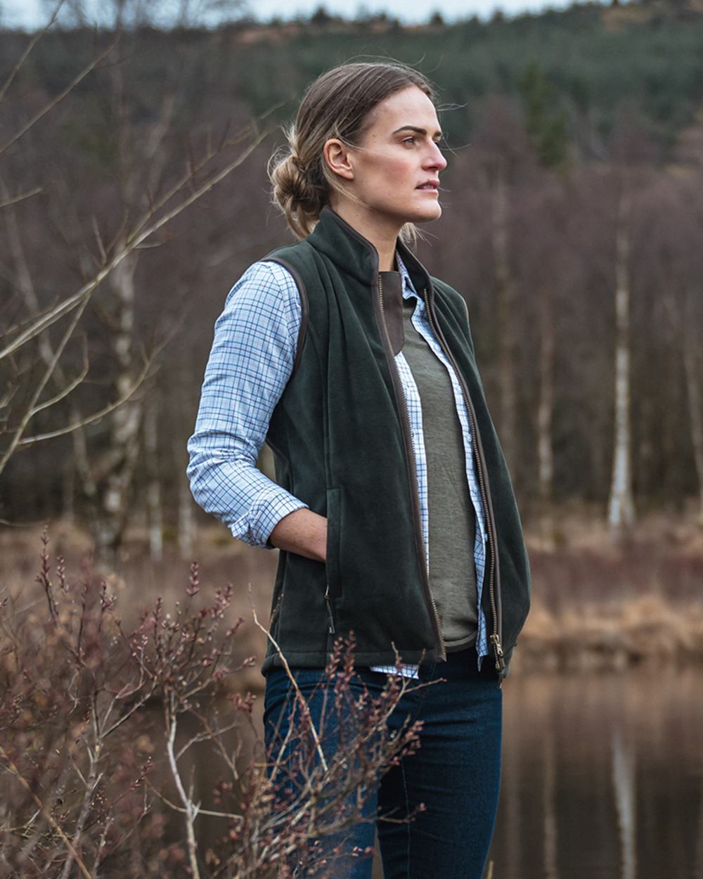 Pine Green Coloured Hoggs of Fife Stenton Ladies Fleece Gilet on lake
background 