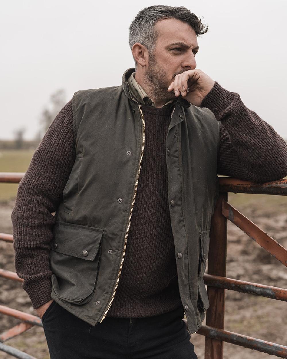 Olive Coloured Hoggs of Fife Waxed Waistcoat on countryside background 