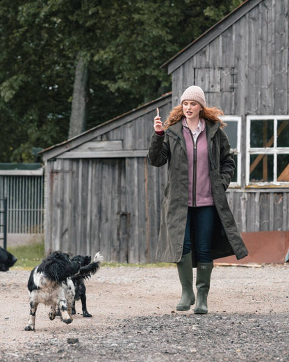 Dark Olive coloured Hoggs of Fife Womens Ardross Pro Long Riding Coat on farm background 