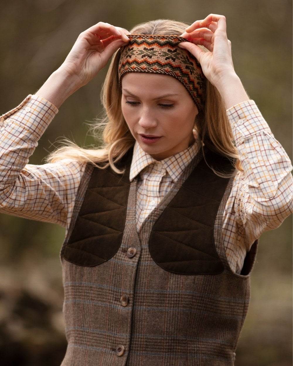 Dark Olive coloured House of Cheviot Lady Fairisle Headband on blurry background 