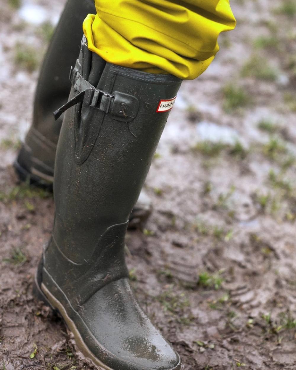 Dark Olive coloured Hunter Mens Balmoral Neoprene Adjustable Wellington Boots on mud background 