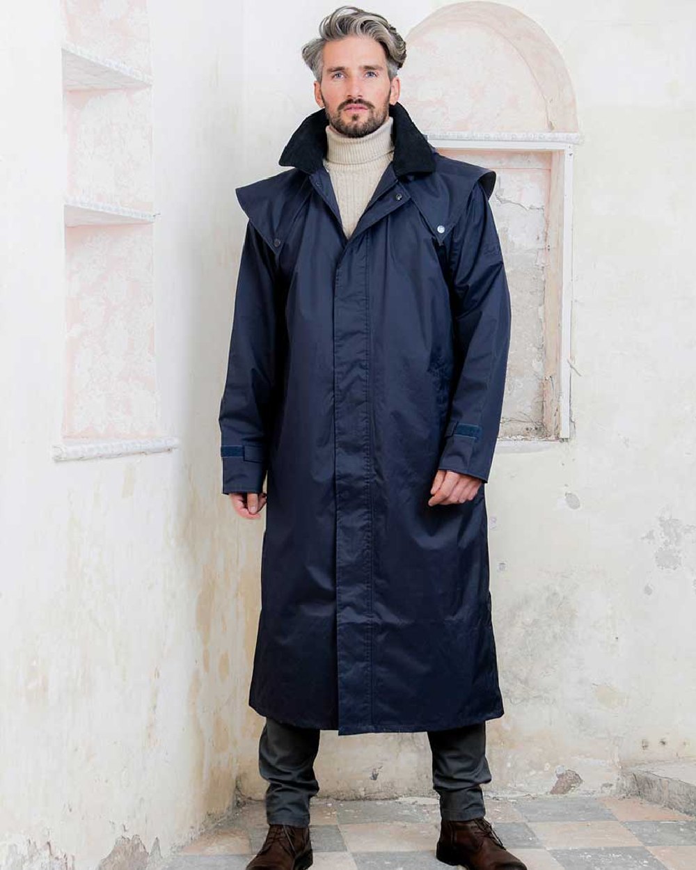 Navy coloured Jack Murphy Lambourne Mens Long Bush Coat on wall background 